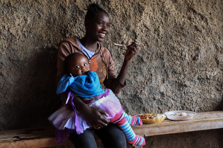 Una madre adolescente keniana almuerza con su bebé en brazos durante su pausa para el almuerzo en la Escuela Secundaria de Niñas Serene Haven, en Kiawara en Kieni, Nyeri, Kenia, el 10 de febrero de 2021.
