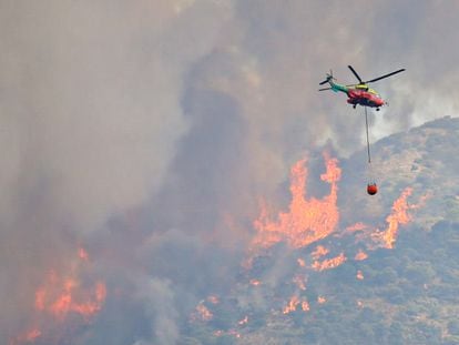 Un helicóptero transporta agua para combatir el incendio forestal en la sierra de Mijas en Alhaurín el Grande (Málaga), este viernes.