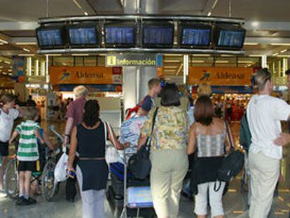 Varias personas observan el panel de horarios del aeropuerto de Mallorca, que sufrió graves retrasos.