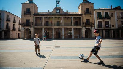 Dos niños juegan al fútbol en la plaza del Burgo de Osma, en Soria.