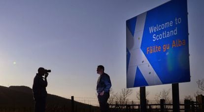 Un hombre se fotografía frente a un cartel que da la bienvenida a Escocia.
