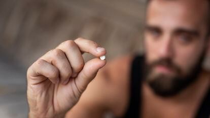Un hombre sujeta una pastilla de éxtasis o MDMA.