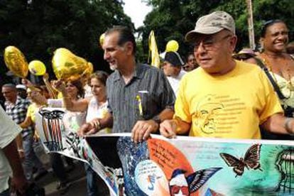 René González (c), el único de los cinco agentes que está en libertad y que vive en Cuba, después de pasar 13 años en la cárcel, su esposa, Olga Salanueva (i), y Miguel Barnet (d), presidente de la Unión de Escritores y Artistas de Cuba (UNEAC), encabezan una simbólica marcha de cientos de personas hasta la sección de Intereses de EE.UU. en La Habana (Cuba).