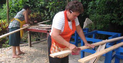 Una mujeres lijan madera para construir una cocina solar.