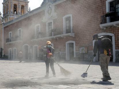 Empleados de limpia barren la ceniza volcánica de una plaza en la ciudad de Atlixco, en el Estado de Puebla.
