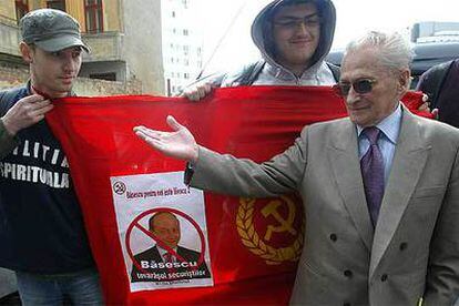 El antiguo opositor Ticu Dumitrescu, seguido por jóvenes con una bandera del régimen de Ceaucescu, el pasado jueves en Bucarest.