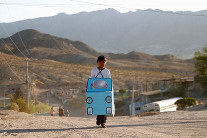 Jazmin, de nueve años, con un coche de cartón para jugar camino de la escuela en Ciudad Juárez (México).