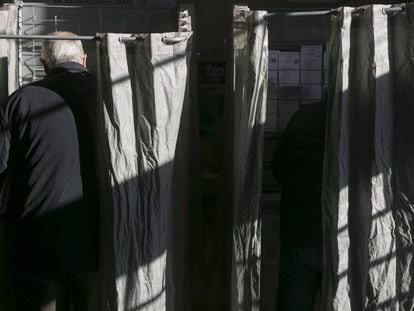Dos votantes escogen sus papeletas en una cabina durante las elecciones en Cataluña de 2017.