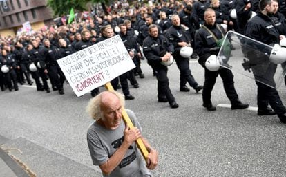 Un manifestante marcha con una pancarta que lee "lo que pasa en el estado constitucional si la policía ignora las decisiones de la corte" cerca de la policía antidisturbios, en Hamburgo. 