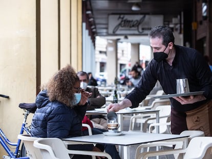 Un camarero sirve un café a una clienta en la Cafetería Tristana, durante el primer día de apertura de bares y restaurantes en Badajoz, Extremadura.