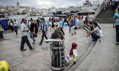 Un ni&ntilde;o sirio refugiado mira a su madre recoger basura en Estambul.