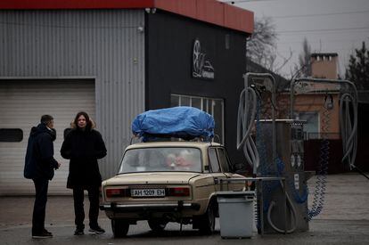 Ciudadanos de Mariupol llenan el depósito de un coche lleno de enseres, este jueves.