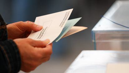 Una persona sostiene papeletas electorales frente a las urnas, a 28 de mayo de 2023.