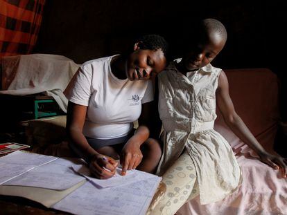 Jackline Bosibori, de 17 años, ayuda a su hermana Angela, de 12, con los deberes del colegio, en su casa del barrio de Kibera, en Kenia. En esta imagen, de septiembre de 2020, la adolescente estaba embarazada de siete meses.