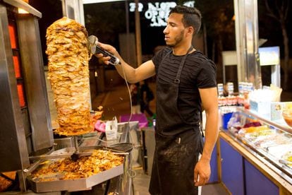 Hicham trabaja en un puesto de kebab en la feria de una ciudad andaluza este verano.