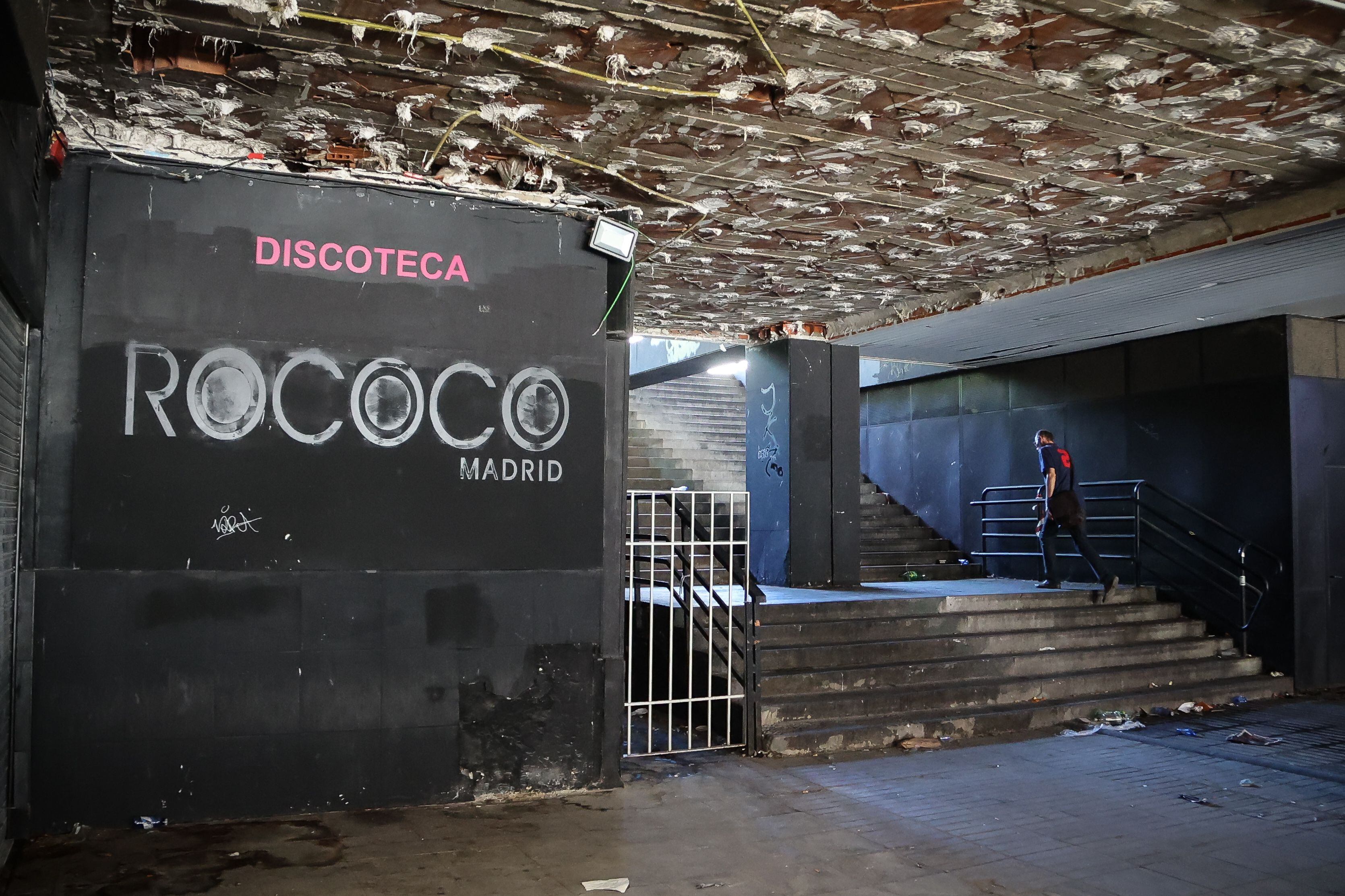 Un hombre sube las escaleras junto al cartel de una de las discotecas de los bajos, en evidente estado de abandono.