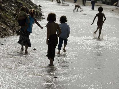 Varios niños chapotean en una zona inundada de la Cañada Real.