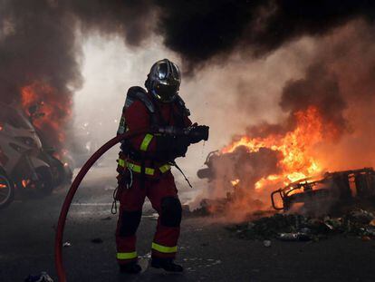 Un bombero junto a varias motos ardiendo en París.