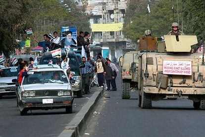 Una caravana electoral de partidarios del gran ayatolá Ali al Sistani pasa junto a un convoy militar de EE UU en Bagdad.