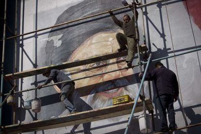 Trabajadores pintan un mural con la imagen de Jamenei.