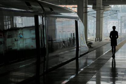 Una azafata espera en un andén junto a un tren bala de alta velocidad de China Railway (CRH) que cubre el trayecto desde Pekín hasta Tianjin, en la Estación Sur de Pekín (China).