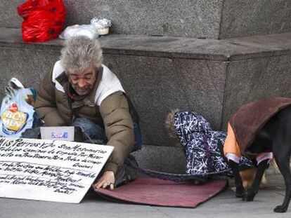 Un indigente, con dos perros, mendigando en una calle de Madrid.