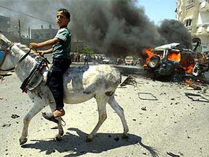 Un niño palestino pasa montado en un burro ante el coche del líder de Hamás, Abdelaziz Rantisi, tras el ataque israelí en Gaza, ayer.