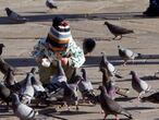 Un niño da de comer a un grupo de palomas en Pontevedra que este viernes presenta un tiempo primaveral.