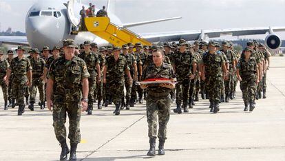 El coronel Blázquez y una soldado portan la última bandera española que ondeó en Istok de la misión, a su regreso en la base aérea de Getafe.