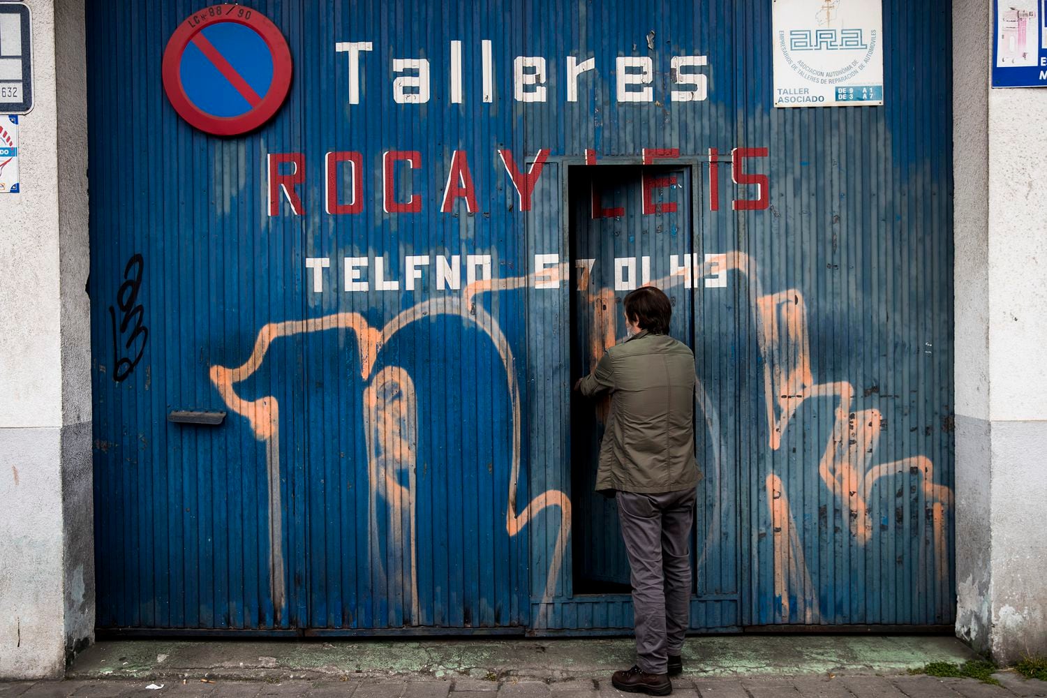 Un trabajador autónomo que regenta un taller mecánico en Santiago de Compostela cierra la puerta de su negocio tras acabar unos trabajos pendientes este viernes.