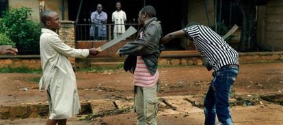 Dos milicianos musulmanes armados con machetes cachean a un cristiano en en barrio de Miskine, en Bangui.