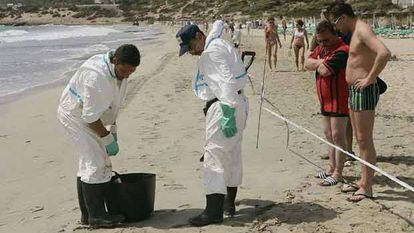 Varios operarios limpian de residuos contaminantes la playa de En Bossa (Ibiza).