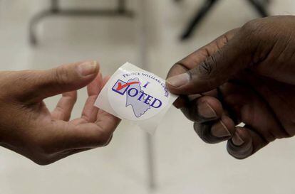 Un enquestador dóna un adhesiu a un votant durant les eleccions presidencials a Dumfries, Virgínia.
