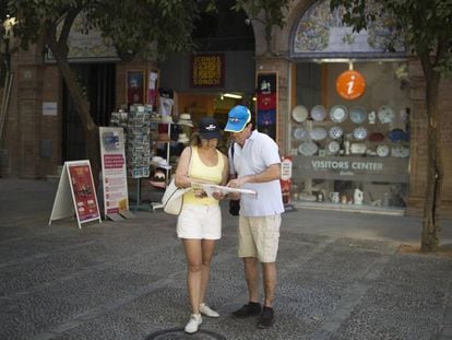 Una pareja consulta un mapa en Sevilla, frente a un punto de información turística.