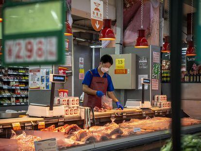 Un comerciante corta la carne en un supermercado en Pekín.