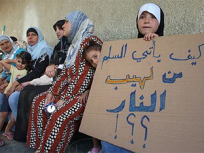 Una desplazada en una escuela de Beirut, con un cartel en el que se lee: "¿Cómo puede la paz nacer de las llamas?".