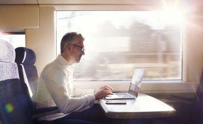 Un hombre trabaja en el ordenador mientras viaja en tren.