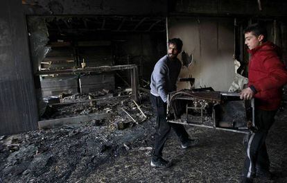 Varios empleados limpian un comercio de máquinas recreativas en Atenas, quemada durante los disturbios.
