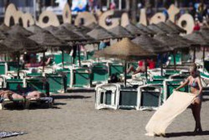 Una mujer disfruta del buen tiempo en la playa de la Malagueta, en M&aacute;laga.