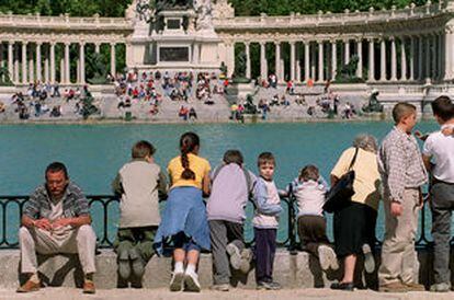 Visitantes del parque del Retiro contemplan el estanque tras la limpieza de su fondo.