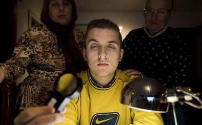 Fran Amor, con sus padres en su casa de Oleiros con la lupa con la que estudia.