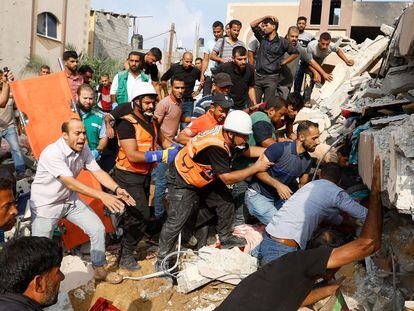 Miembros de los servicios de emergencia y vecinos buscaban víctimas bajo los escombros tras un bombardeo israelí sobre Jan Yunis, en la franja de Gaza, este domingo.