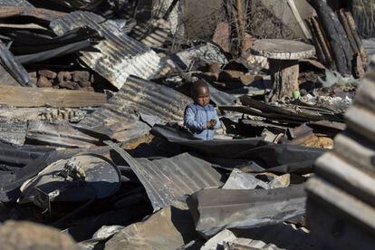 Un niño observa los restos calcinados de su casa, en Sudáfrica.