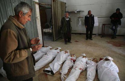 Un hombre reza frente a los cadáveres de varios niños víctimas del último bombardeo del régimen sirio.