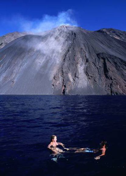 Dos bañistas frente al volcán humeante de la isla de Estrómboli.