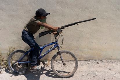 Un niño con un arma simulada monta en bicicleta.