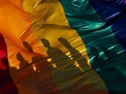 La sombra de unos participantes en una marcha del Orgullo LGTBQ en Managua se refleja sobre la bandera del arco iris, símbolo de la causa.