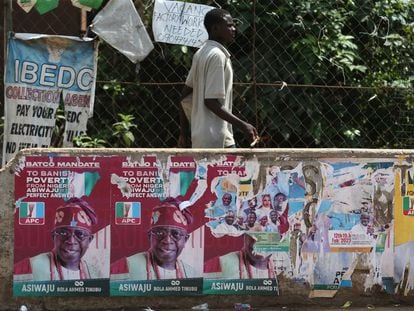 Un hombre camina junto a varios carteles electorales del recién elegido presidente del país, Bola Ahmed Tinubu, en el distrito de Agege en Lagos.