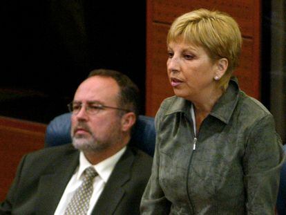Teresa Sáez vota de pie, junto a Eduardo Tamayo, sentado, en sus escaños de la Asamblea de Madrid.