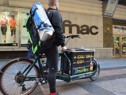 Un repartidor Fnac de envíos de pedidos ecológicos frente a una tienda en Madrid.